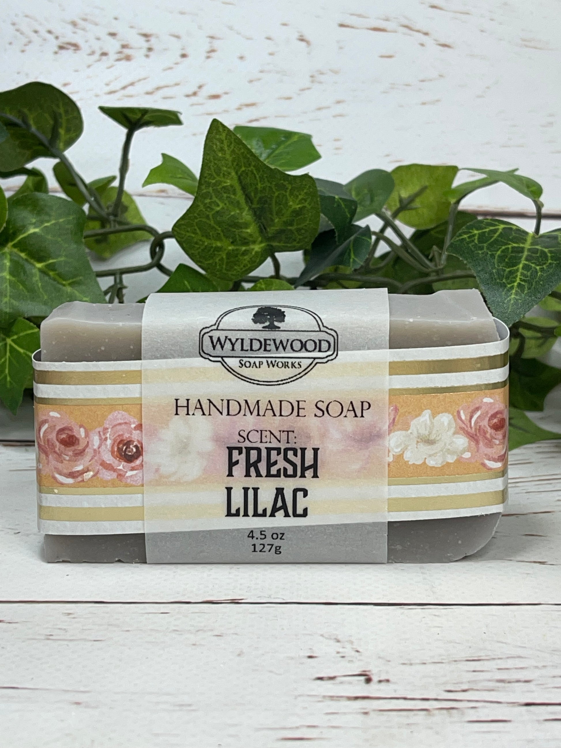 A packaged bar of Fresh Lilac scented soap with a label showing the brand name 'Wyldwood' and an image of pink lilac flowers. The soap is displayed on a white surface with a green leafy background.